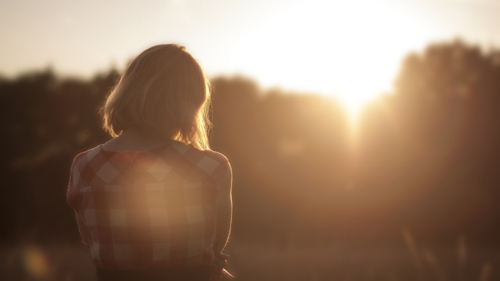 a person standing in front of trees in the sun