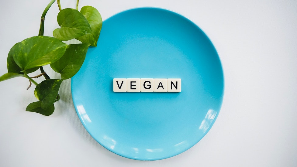 a close up of scrabble letters that say 'vegan' on a blue plate