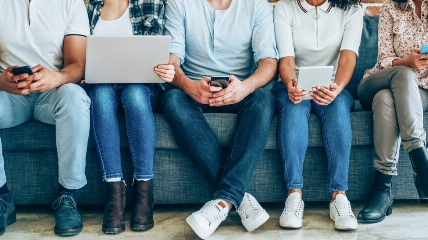 a group of people sitting on a bench using their mobiles