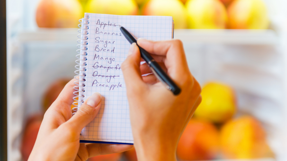 a person holding a piece of paper with a food shopping list