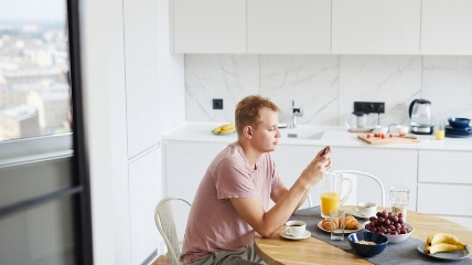 a person sitting at a kitchen table on their phone