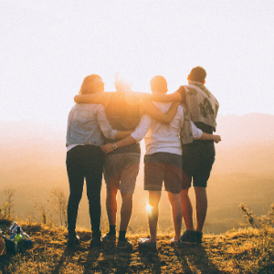 a group of people standing in front of a sunset