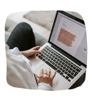 a person using a laptop computer sitting on top of a bed