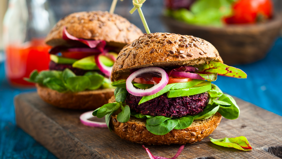 two vegan burgers in a bun on a wooden chopping board