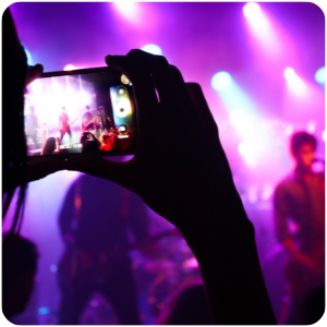 a person videoing a band on stage