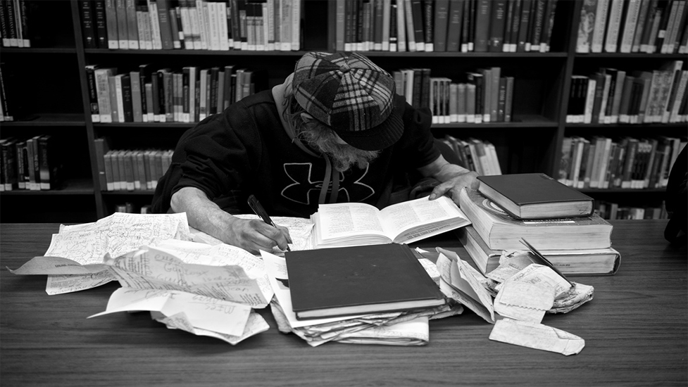 a person using a laptop computer sitting on top of a book shelf