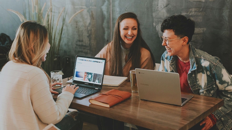 a group of people sitting at a table using a laptop