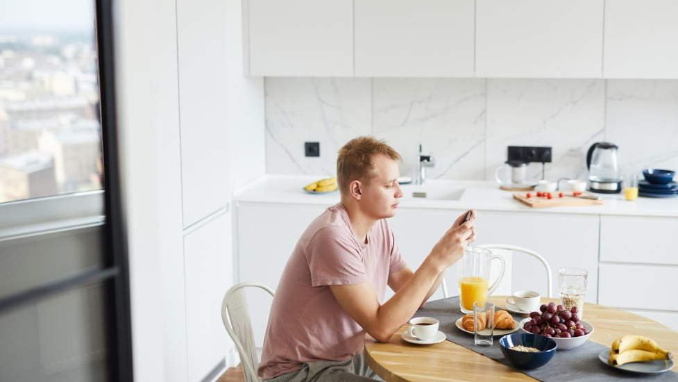 a person sitting at a kitchen table on their phone