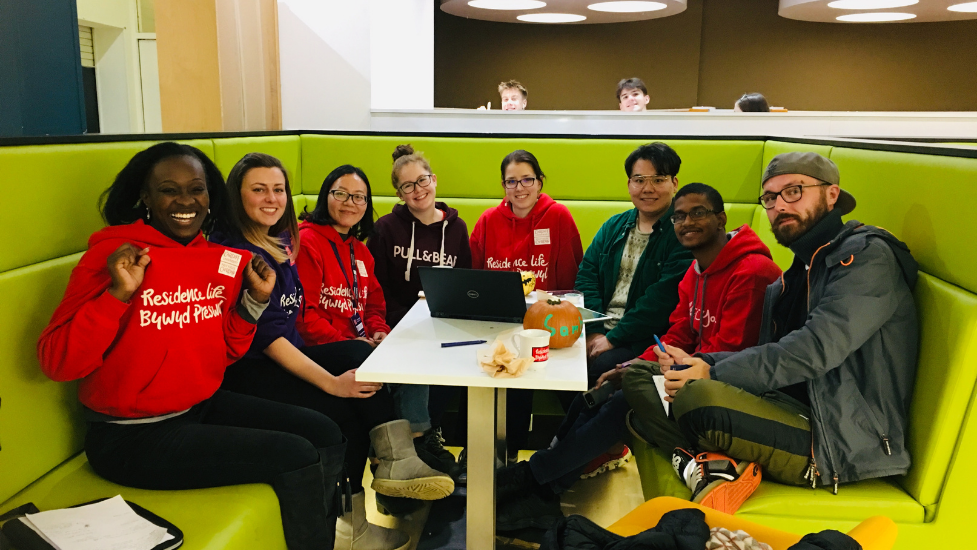 a group of people sat around a table smiling at the camera