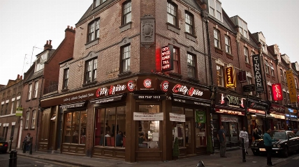 a large brick building with neon lights on Brick Lane