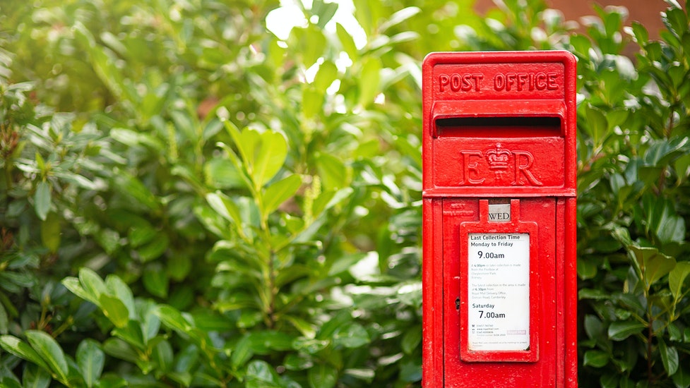 a post box in front of some bushes